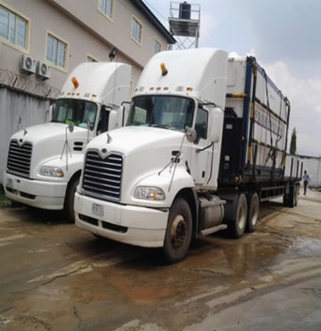Pair of white Mack tractor units with container flatbed at the operations base