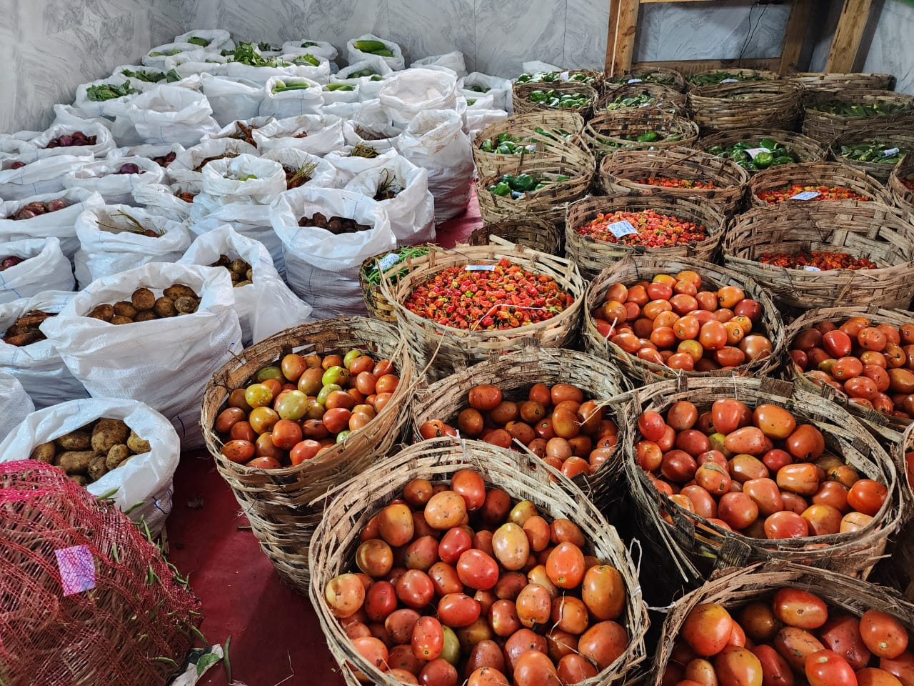 Fresh produce intake — tomatoes, peppers, onions and tubers sorted for the commissary