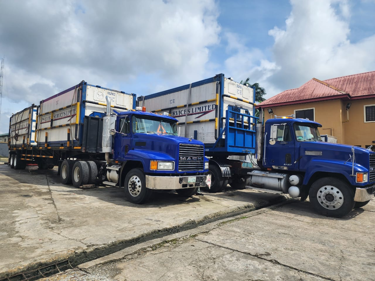 Blue Mack tractor units coupled to branded GGSL flatbed reefer containers at the base